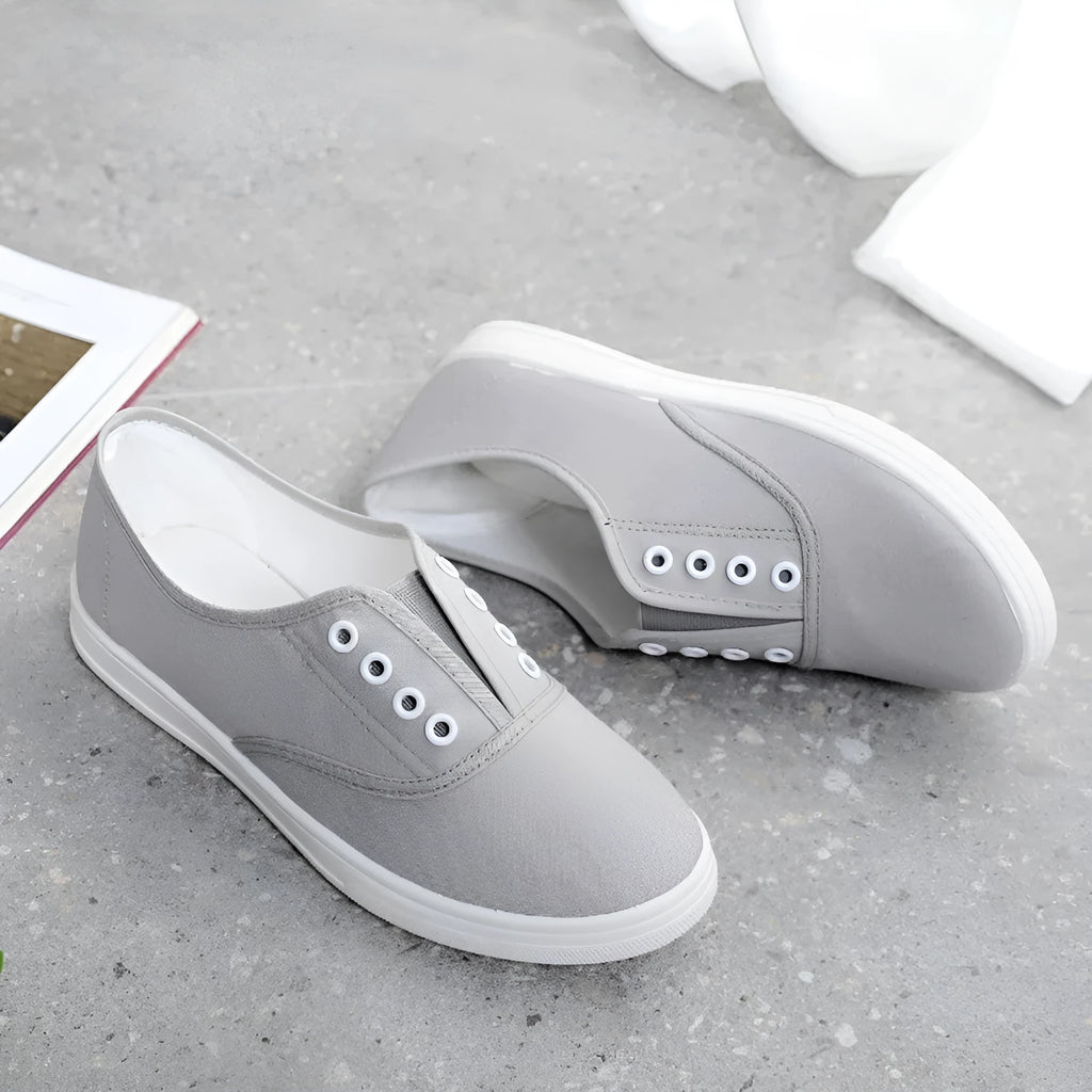 A pair of low-top casual canvas shoes in a flat style, shown in a choice of colours including black, white, grey, and pink.