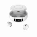 Black wireless semi-in-ear headphones next to their white charging case on a table.