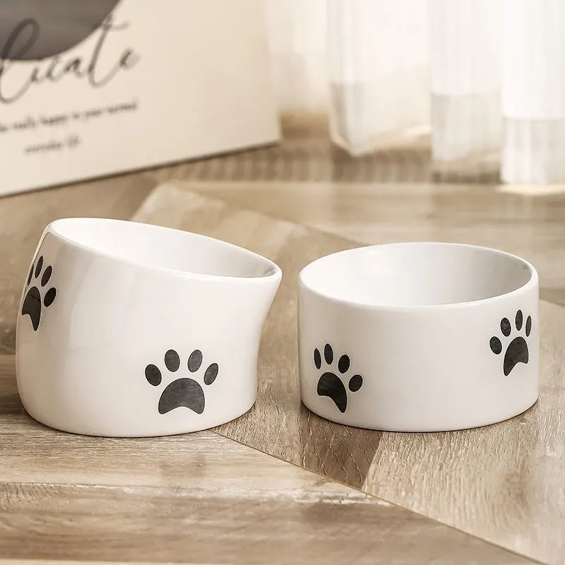 Ceramic cat food bowl with high foot base in a cat's paw print design