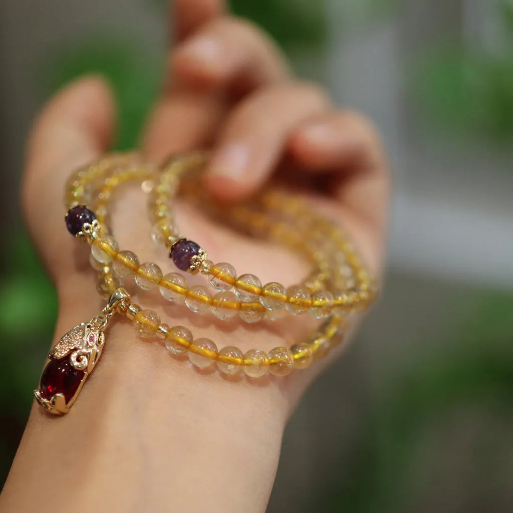 Natural Brazilian rutilated quartz bracelet with gold accents and Chinese-style charms on adjustable cord