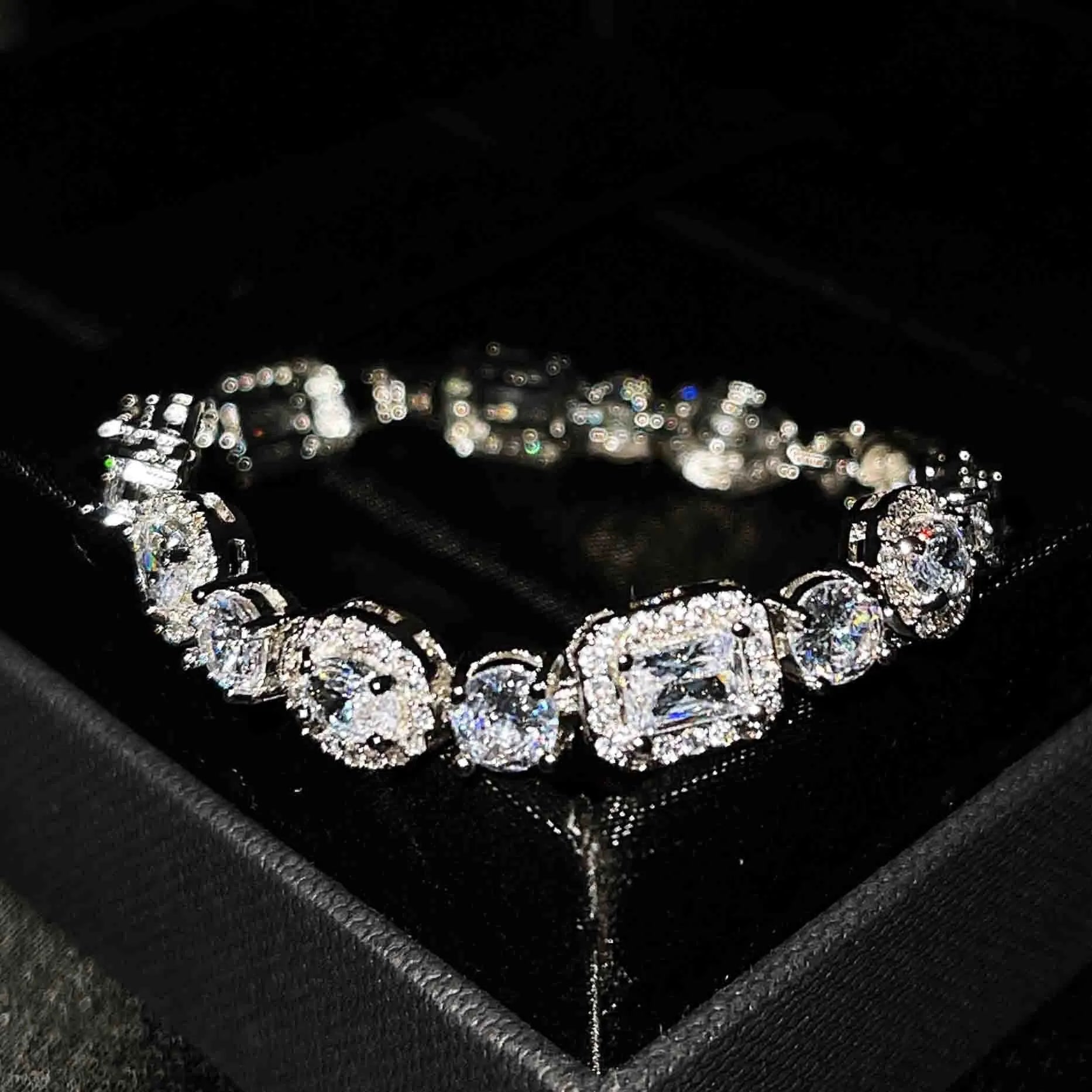 Close-up of a women's geometric silver bracelet with sparkling inlaid zircon stones and a lobster clasp.