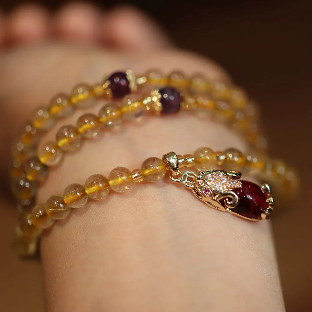 Natural Brazilian rutilated quartz bracelet with gold accents and Chinese-style charms on adjustable cord