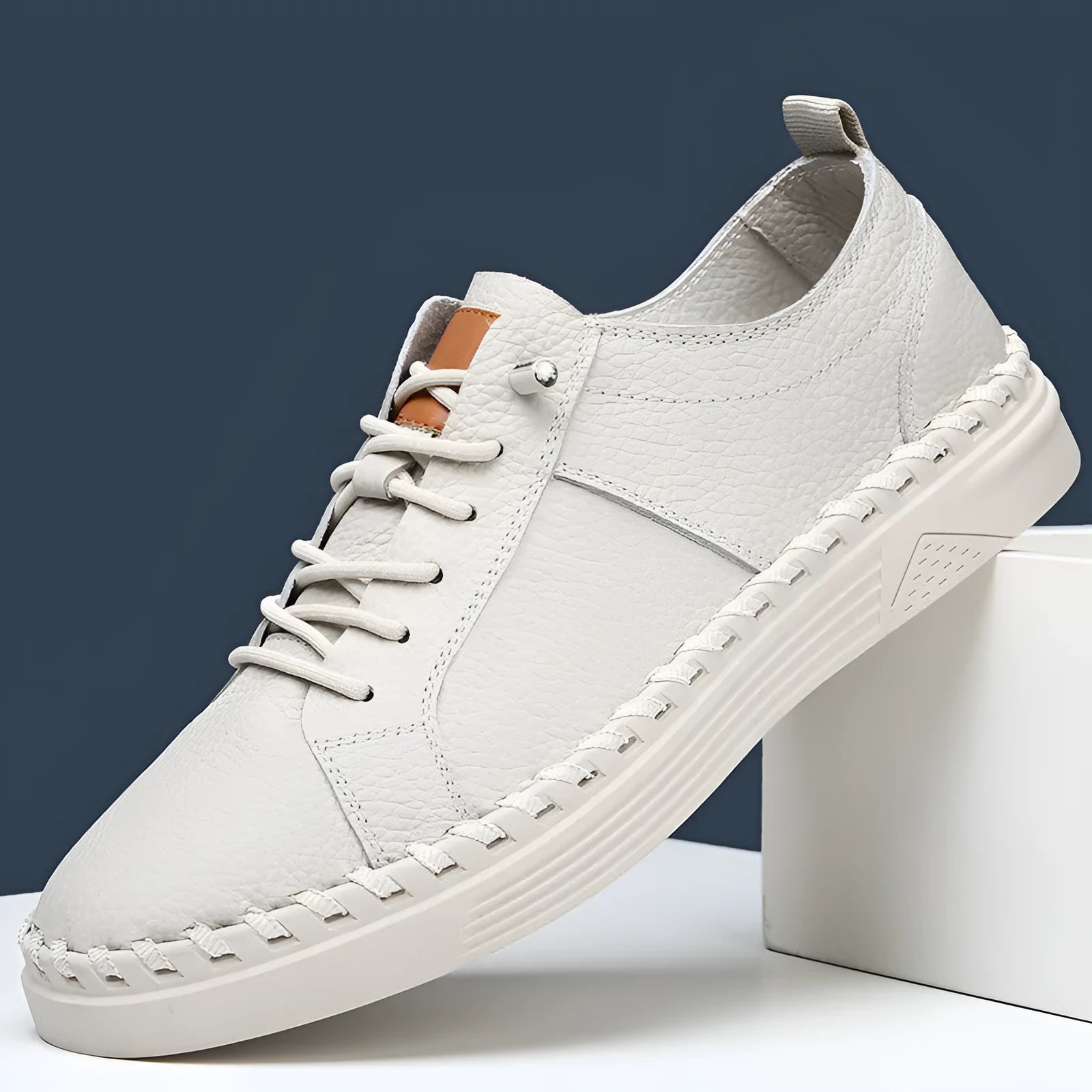 Men's beige and black cowhide leather sneakers with round toe and visible stitching on a white background.