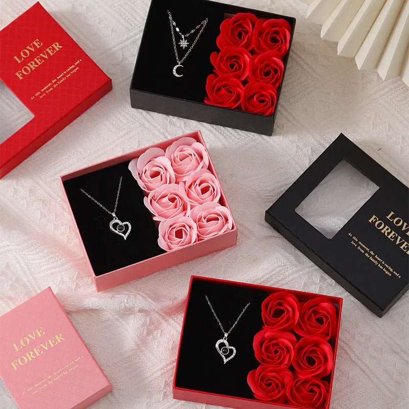Red Valentine's gift box containing six pink soap flowers, with a matching red handbag alongside.