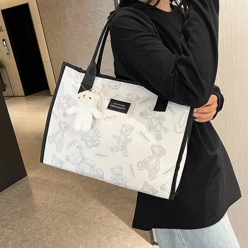 Women's black canvas tote bag with diamond pattern showing horizontal square shape and pendant attachment option