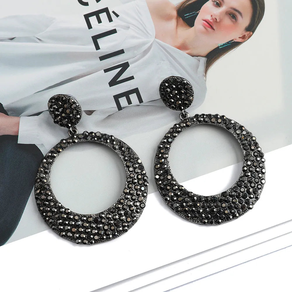 A pair of large round pendant earrings with a cartoon style in a colour metal alloy finish.