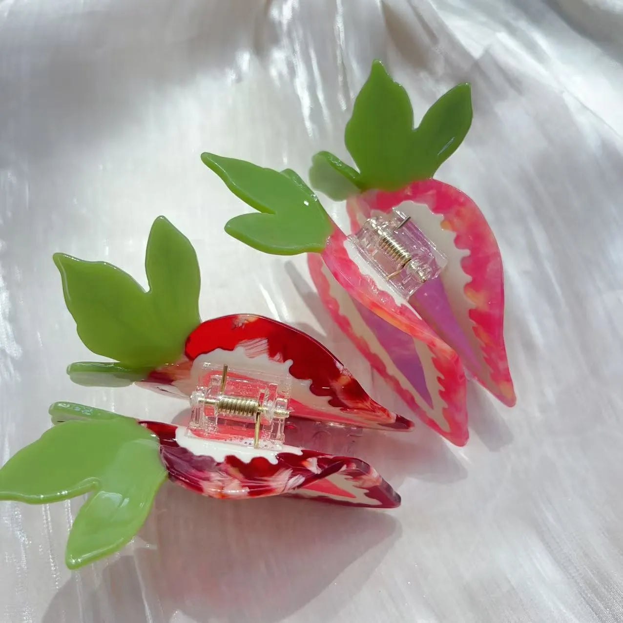 Close-up of a handmade red and pink strawberry hairpin on a pastoral background.