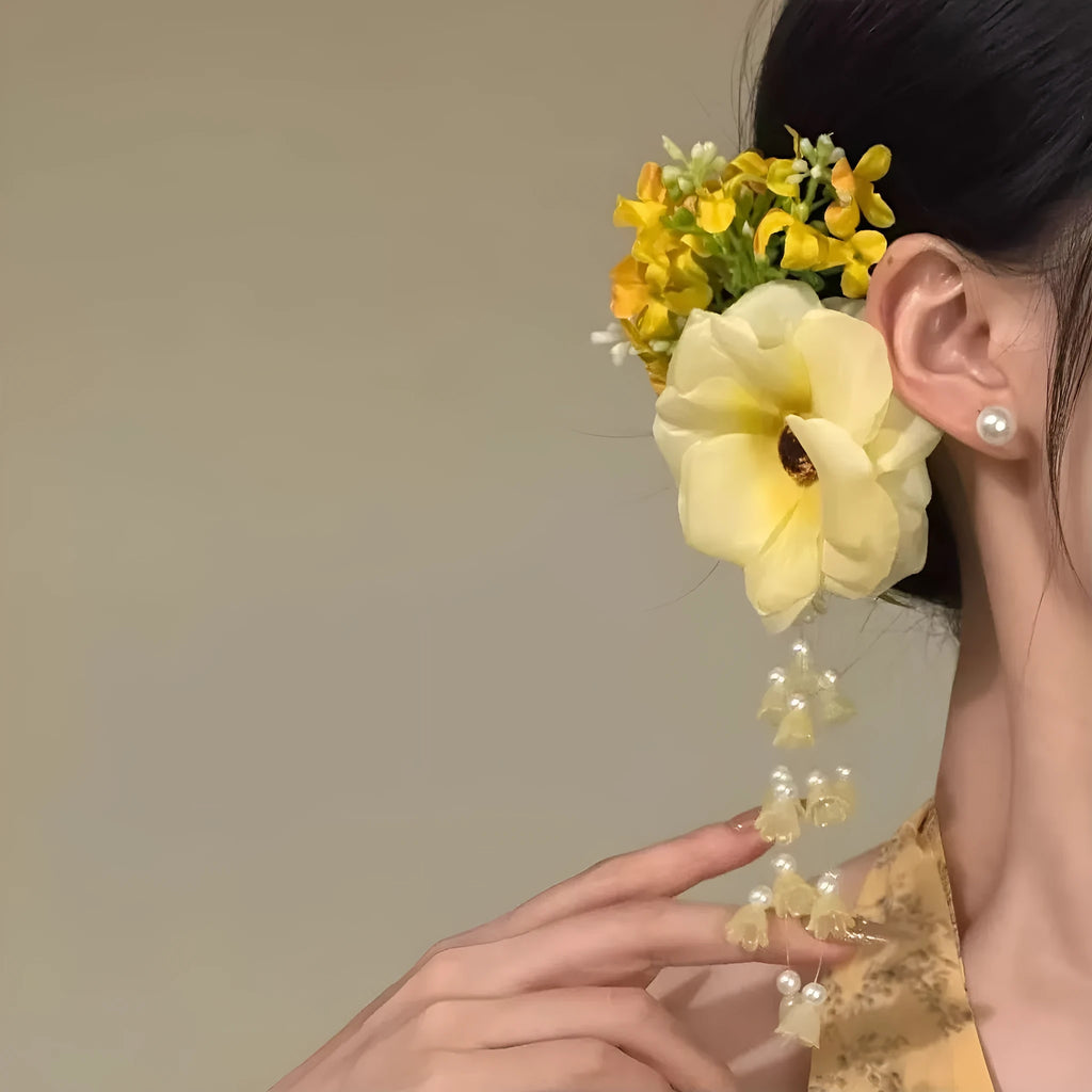 Hand-made yellow and purple flower tassel hair clip with pearl accents on a white background.