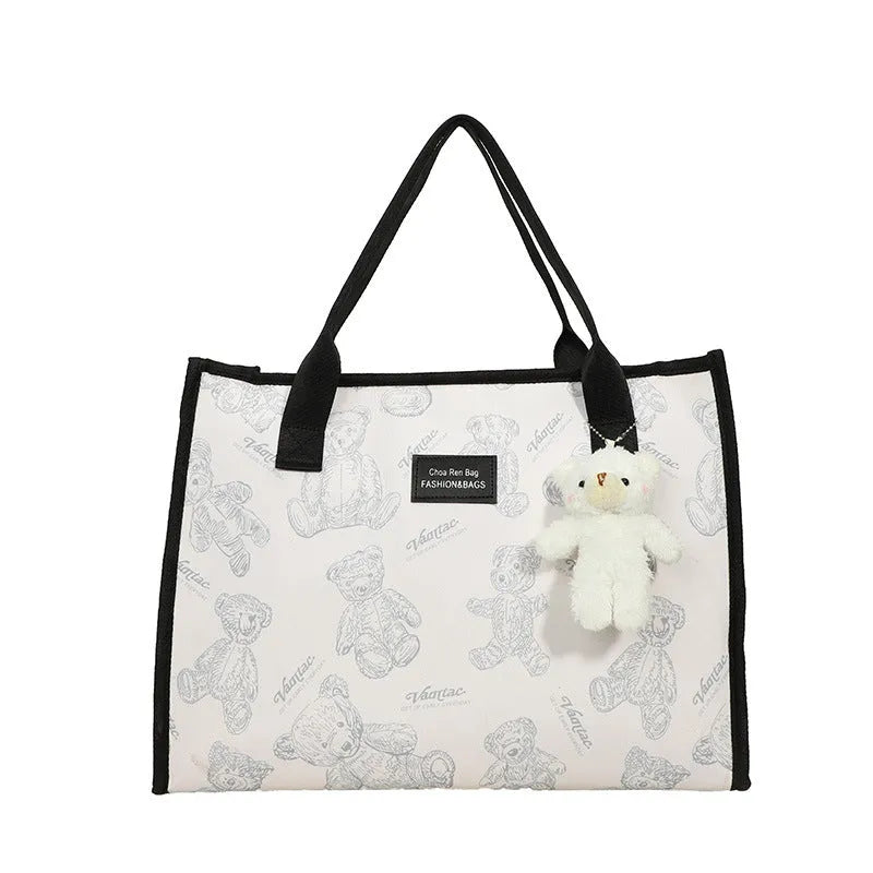 Women's black canvas tote bag with diamond pattern showing horizontal square shape and pendant attachment option