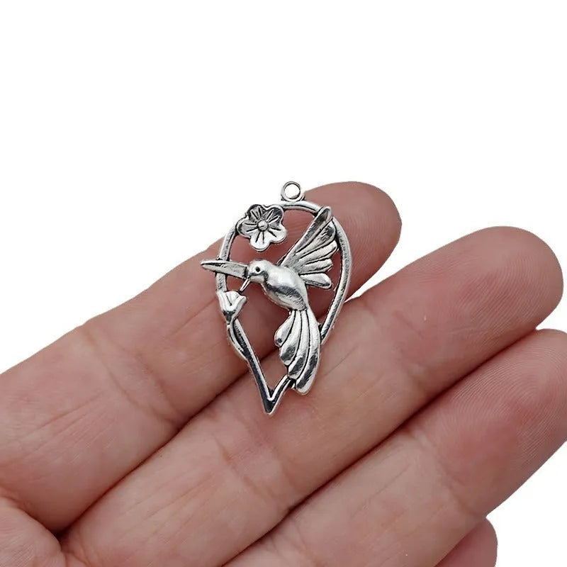 Close-up of a silver-coloured alloy pendant shaped like a magpie bird with detailed feathers, on a white background.