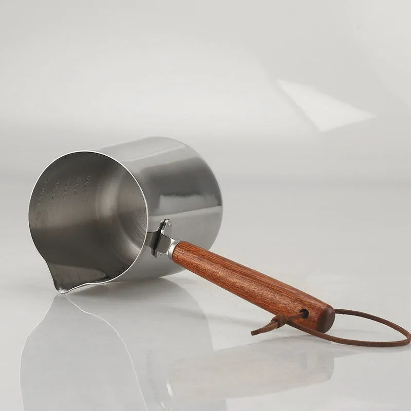 Stainless steel coffee cup with wooden handle and visible millilitre scale markings.