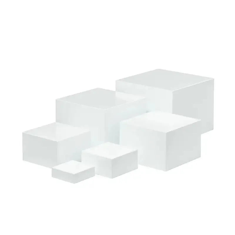 Set of six white plastic stacking cubes for displaying cakes and desserts on a table.