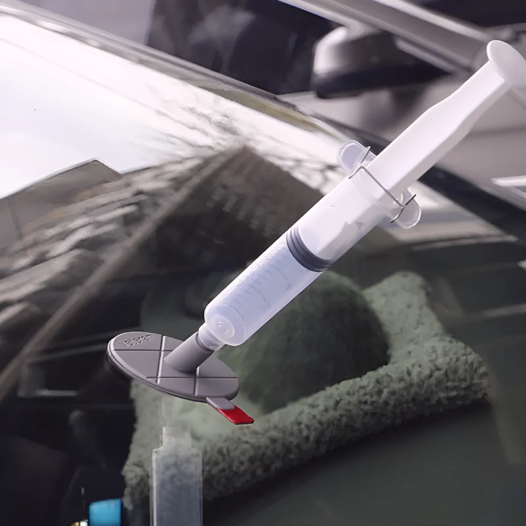 Car windscreen repair kit box containing UV lamp, green resin syringe, injection tools, and yellow bracket.
