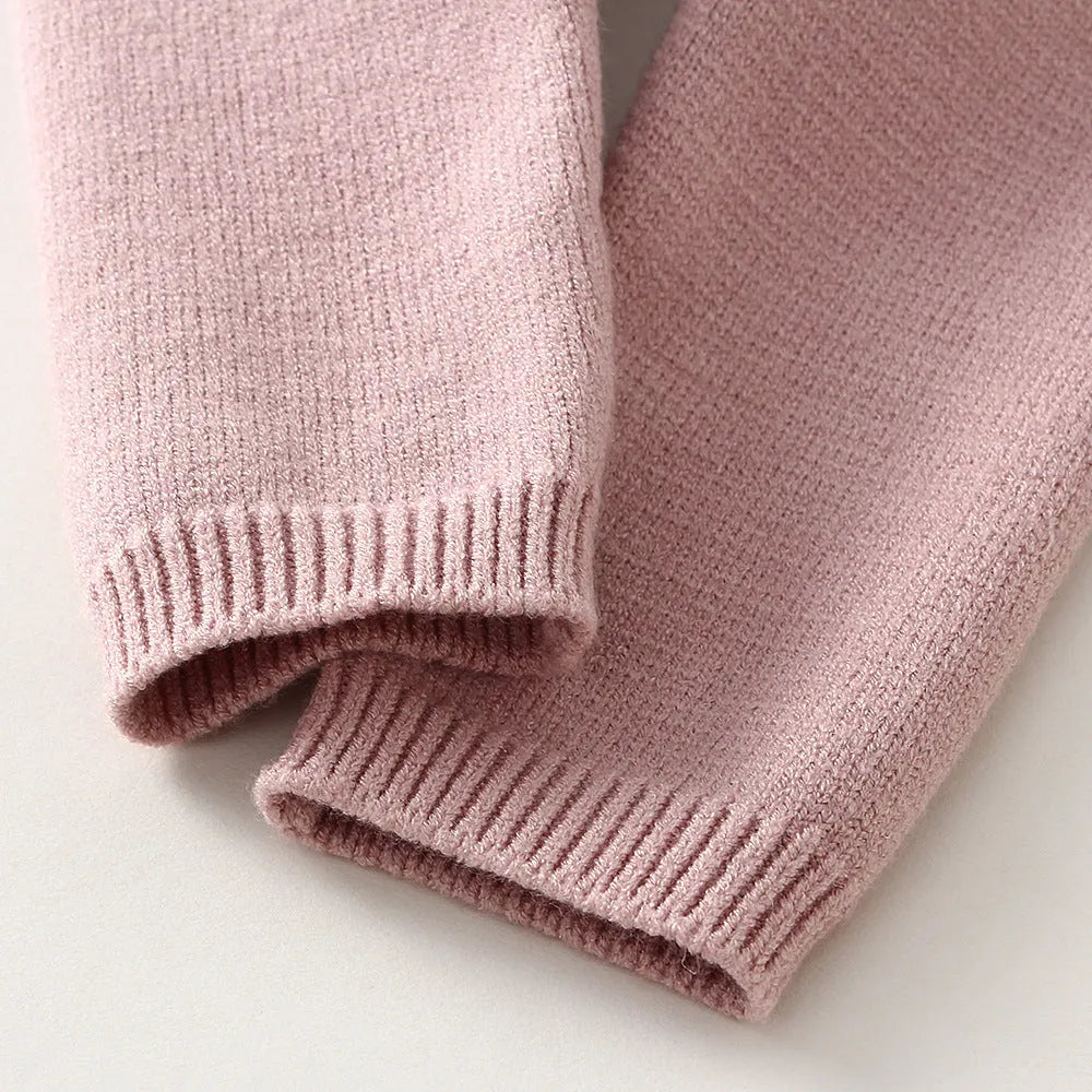 Baby girl wearing a pink knitted pullover sweater and matching trousers set.