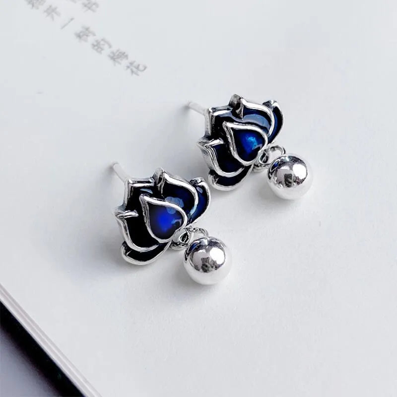 Silver-tone blue lotus flower stud earrings with a dangling seedpod tassel.