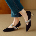 Women's black pointed-toe stiletto heels with an ankle buckle on a rubber sole