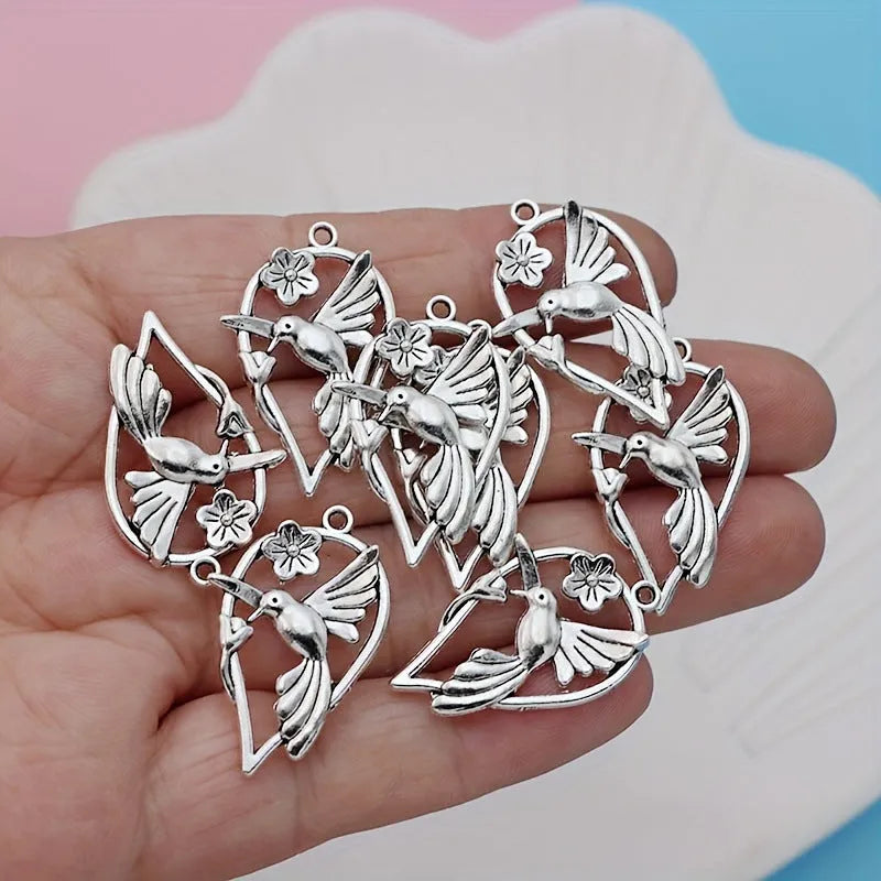 Close-up of a silver-coloured alloy pendant shaped like a magpie bird with detailed feathers, on a white background.