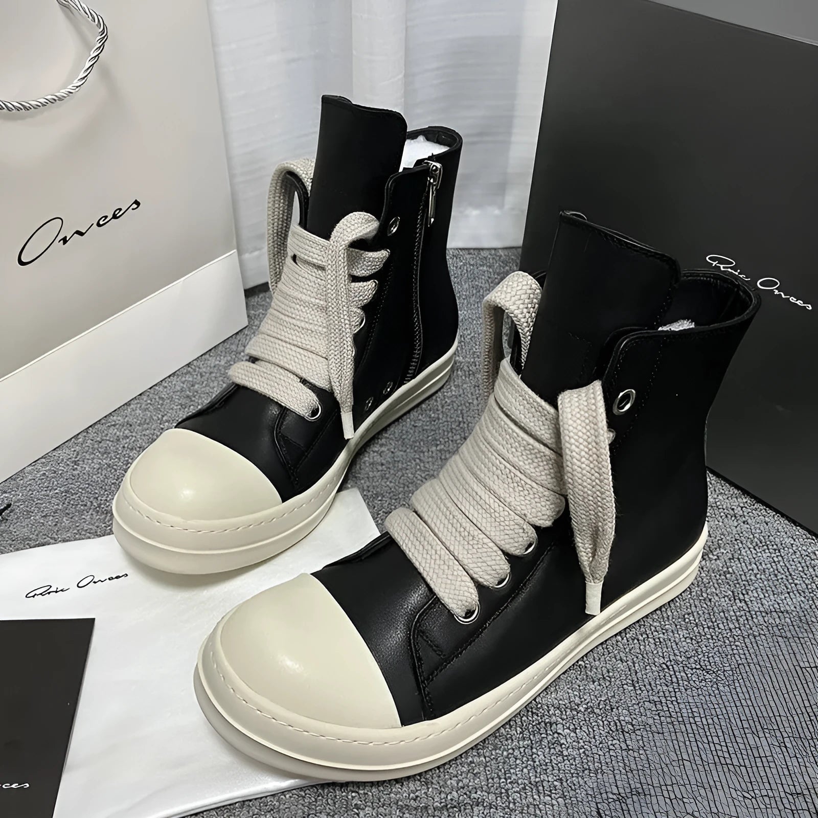 Black high-top genuine leather boots with side zip detail on a white background.
