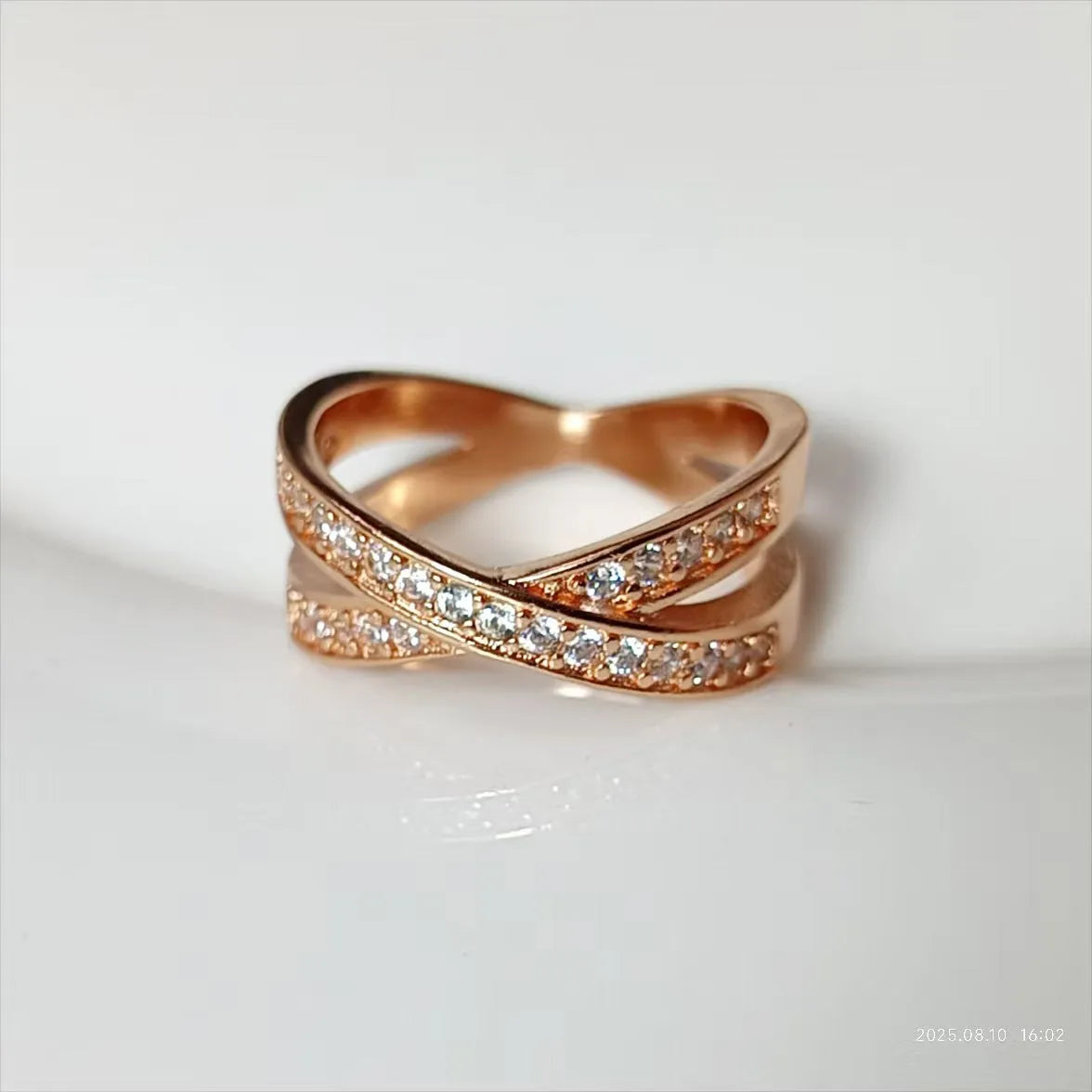 Close-up of a silver metal ring with a geometric cross design featuring small zircon stones.