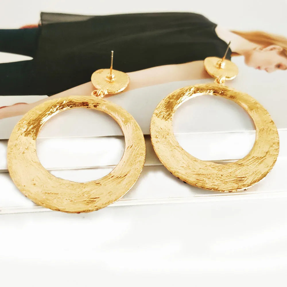 A pair of large round pendant earrings with a cartoon style in a colour metal alloy finish.