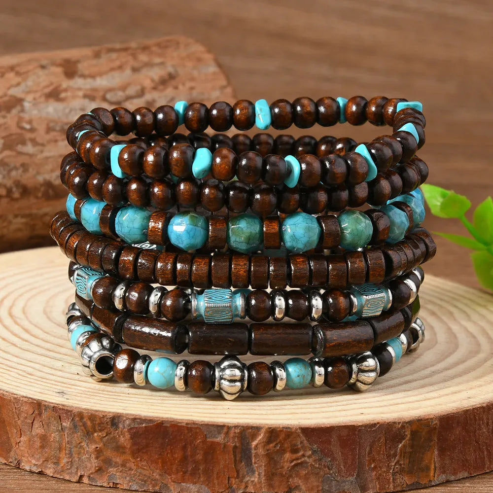 Set of seven multicolour retro bracelets with wooden beads and alloy charms laid flat.