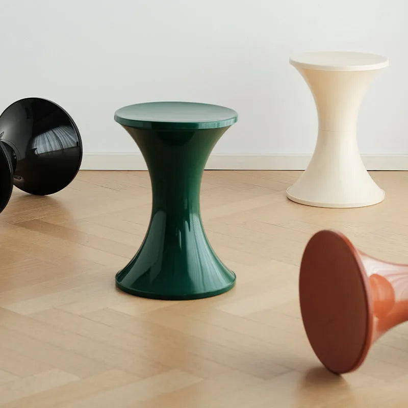 Green plastic hourglass-style shoe changing stool on a wooden floor.