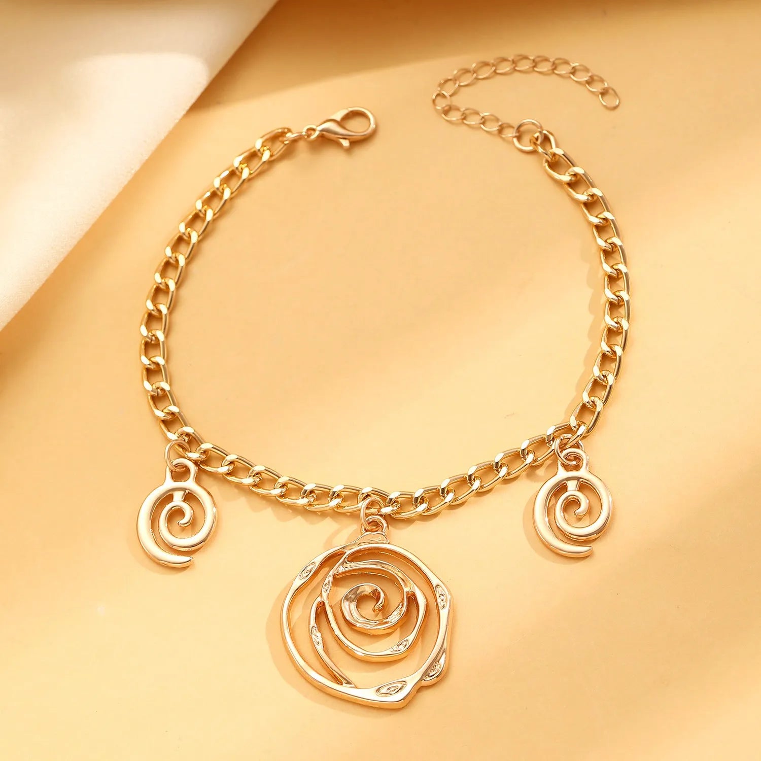 Spiral donut design jewellery set with necklace, bracelet and ear hooks in gold or silver finish