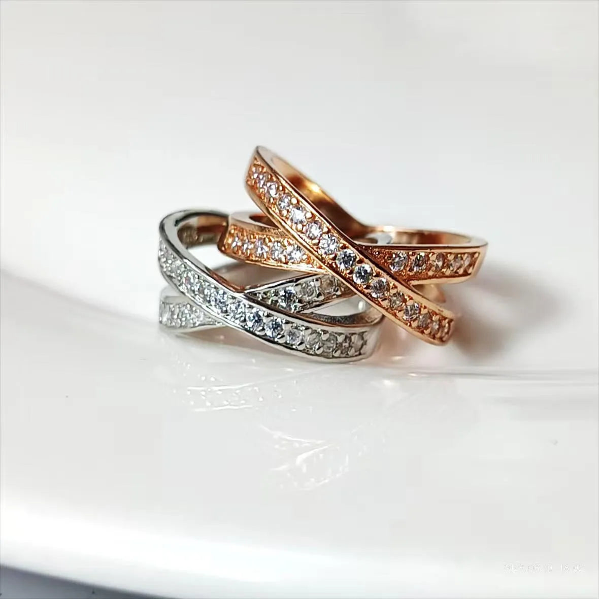 A silver or rose gold plated copper ring with a geometric cross design and micro-inlaid zircon stones.