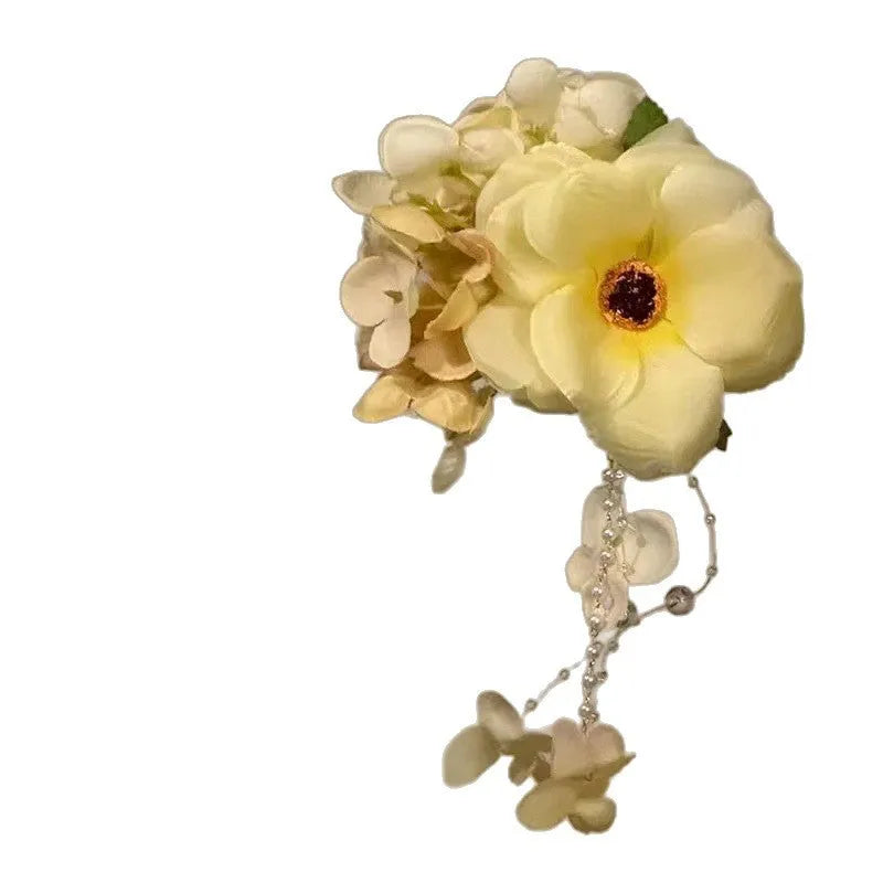 Hand-made yellow and purple flower tassel hair clip with pearl accents on a white background.