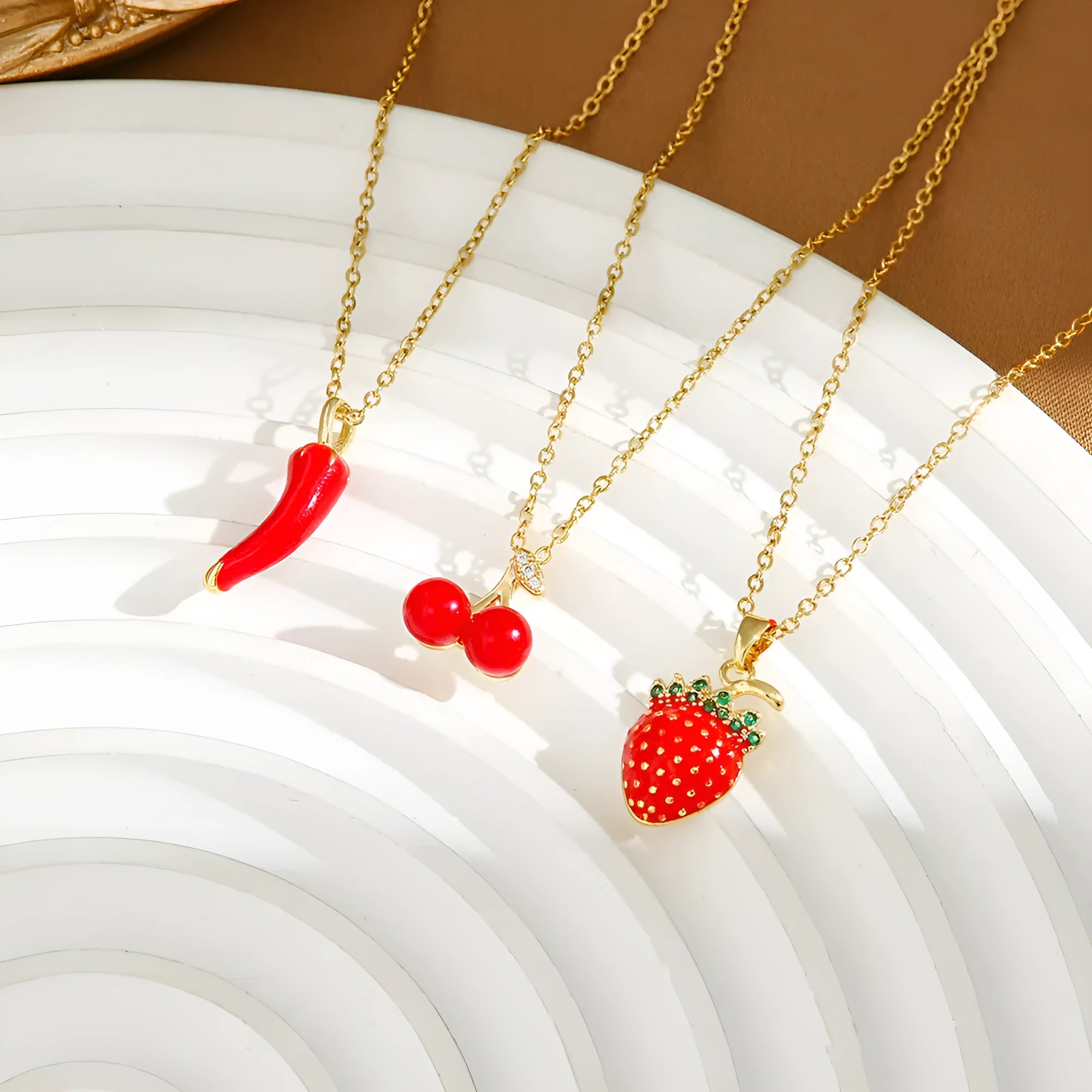 Delicate red fruit charm necklace on a titanium steel O-ring chain, showing gold and steel colour options.