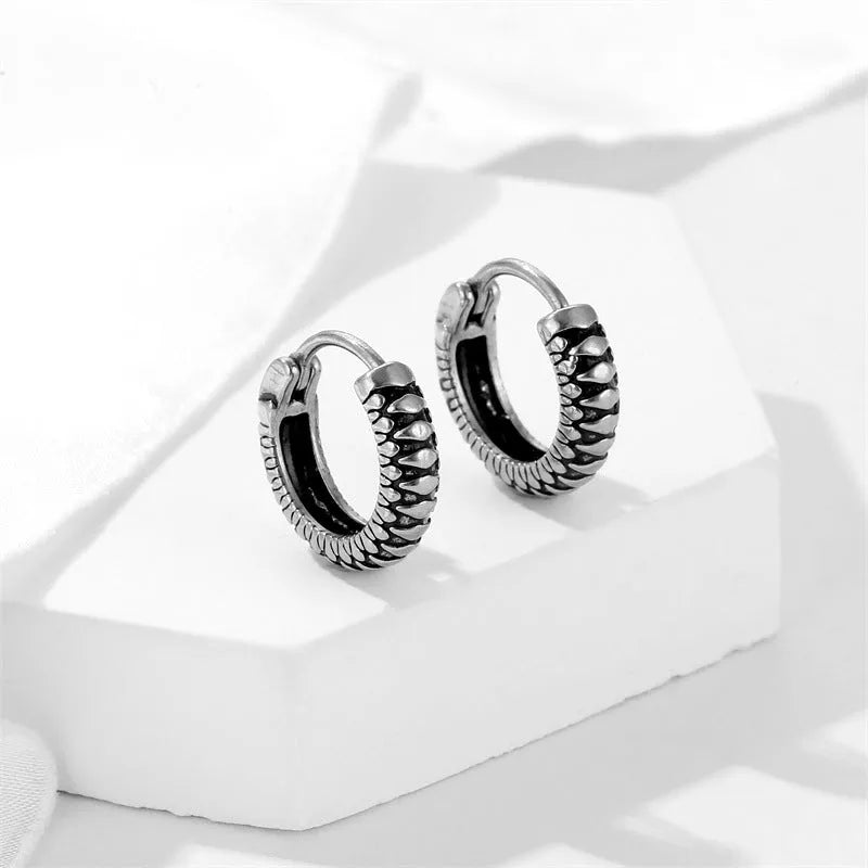 A pair of silver geometric twist earrings made from stainless steel alloy on a white background.