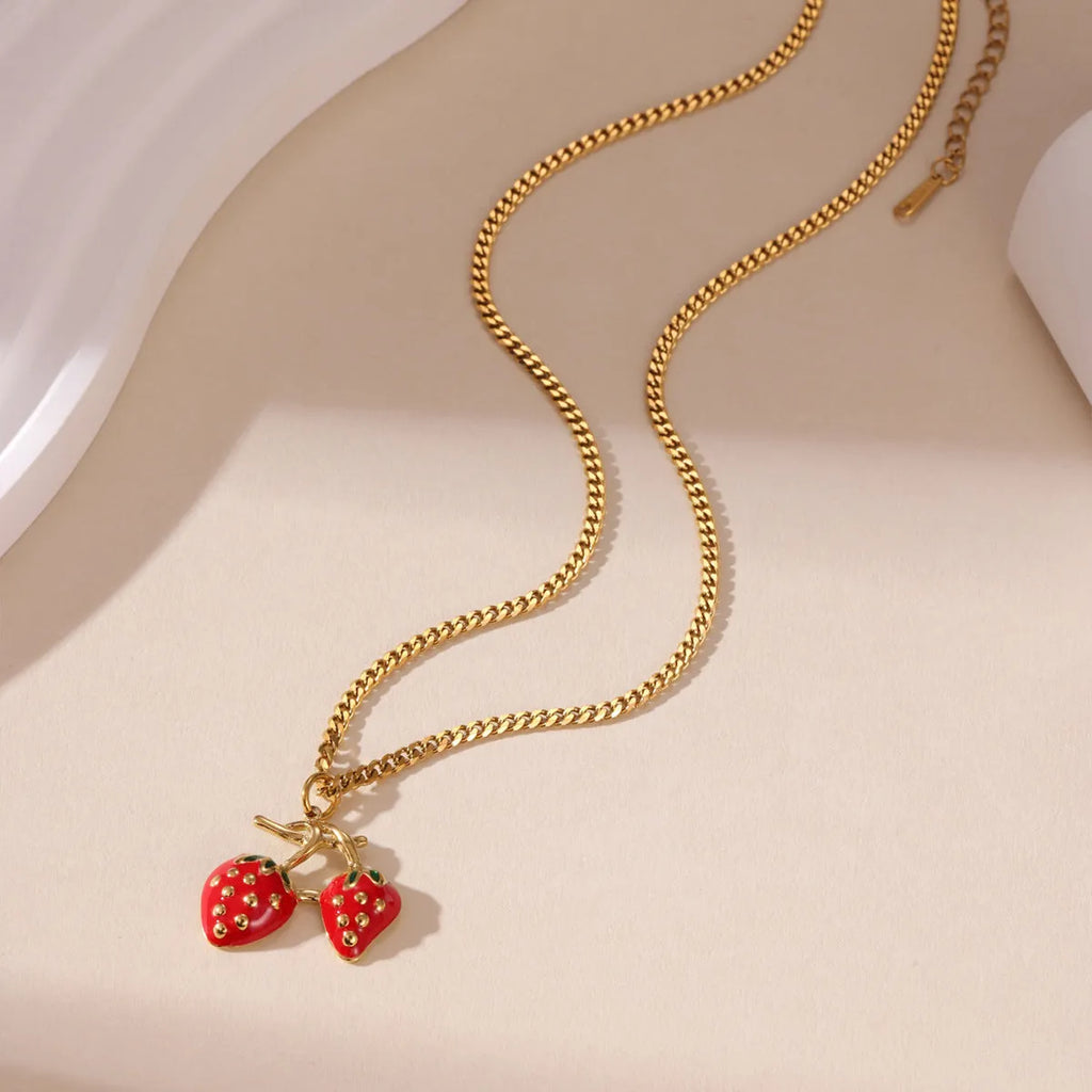 A women's necklace with a detailed strawberry-shaped alloy pendant on a stainless steel chain, shown in red and white gradient colour options.