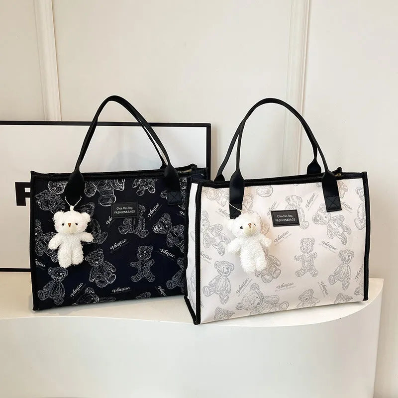 Women's black canvas tote bag with diamond pattern showing horizontal square shape and pendant attachment option