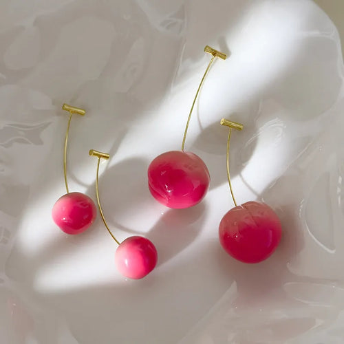 Pair of peach-shaped acrylic fashion earrings with copper posts on a white background.