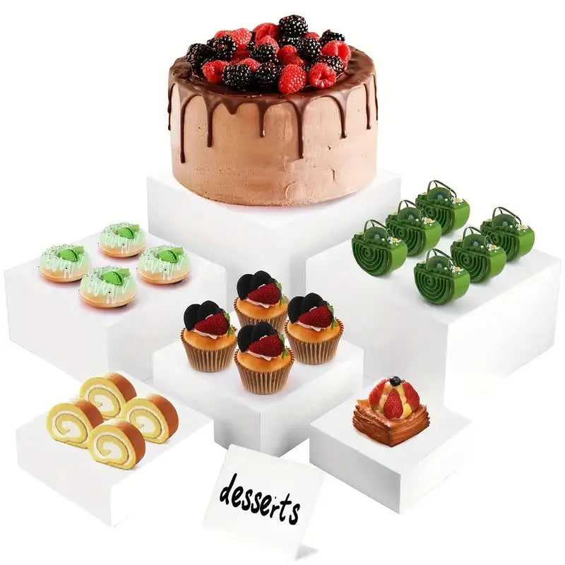Set of six white plastic stacking cubes for displaying cakes and desserts on a table.