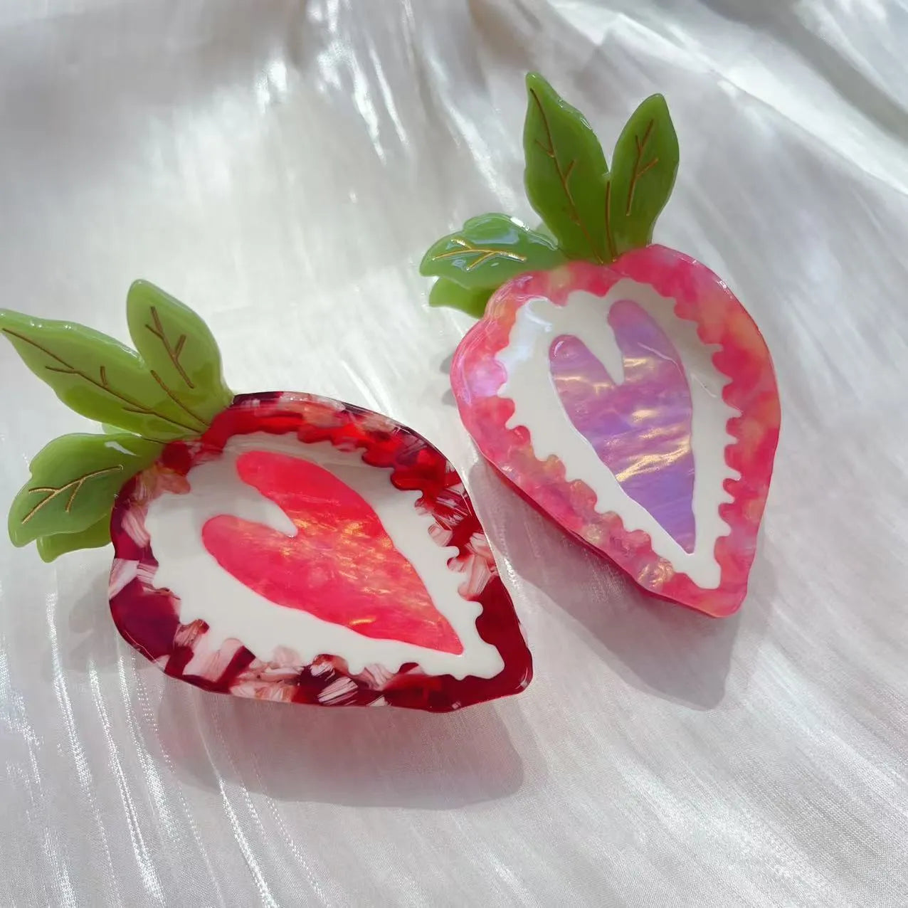 Close-up of a handmade red and pink strawberry hairpin on a pastoral background.