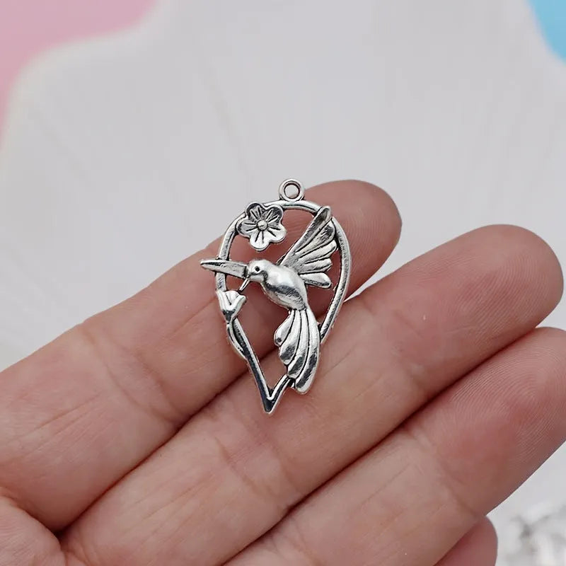Close-up of a silver-coloured alloy pendant shaped like a magpie bird with detailed feathers, on a white background.