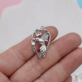 Close-up of a silver-coloured alloy pendant shaped like a magpie bird with detailed feathers, on a white background.