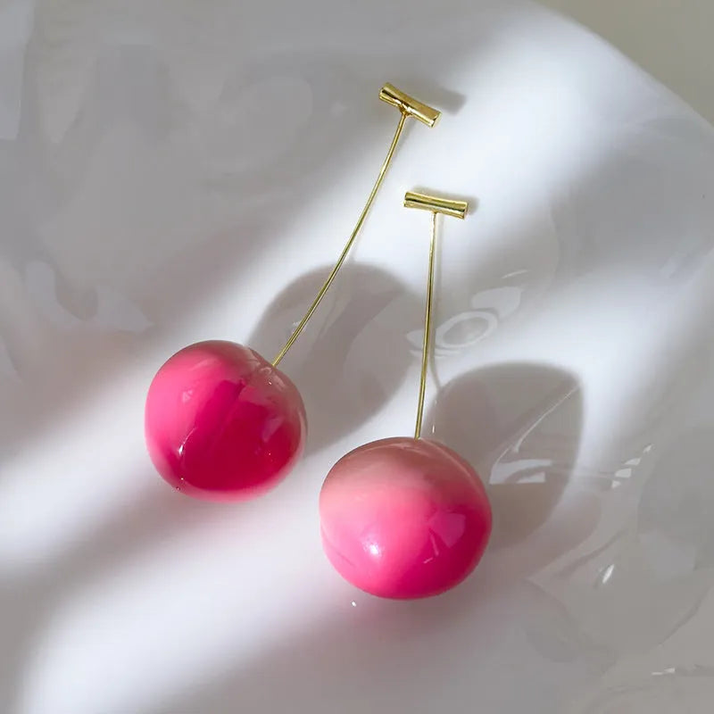 Pair of peach-shaped acrylic fashion earrings with copper posts on a white background.