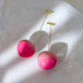 Pair of peach-shaped acrylic fashion earrings with copper posts on a white background.