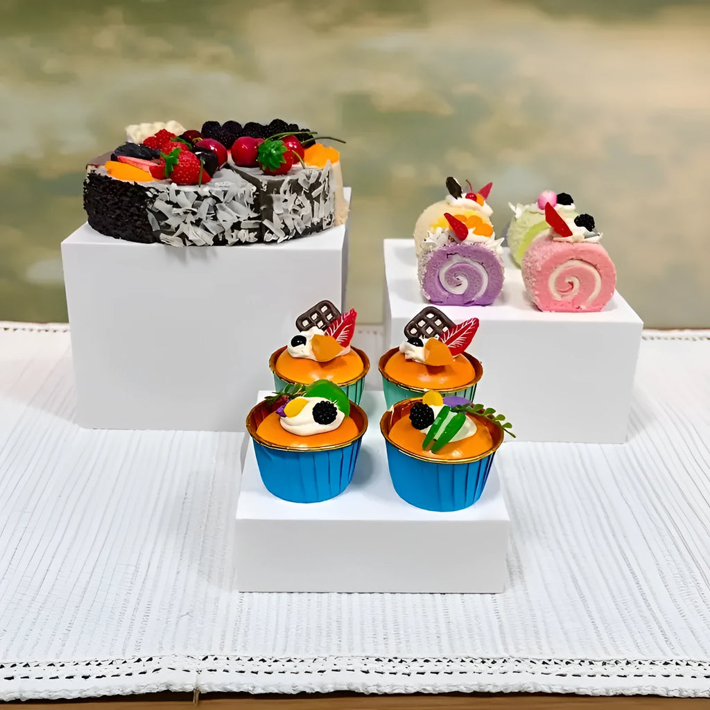 Set of six white plastic stacking cubes for displaying cakes and desserts on a table.