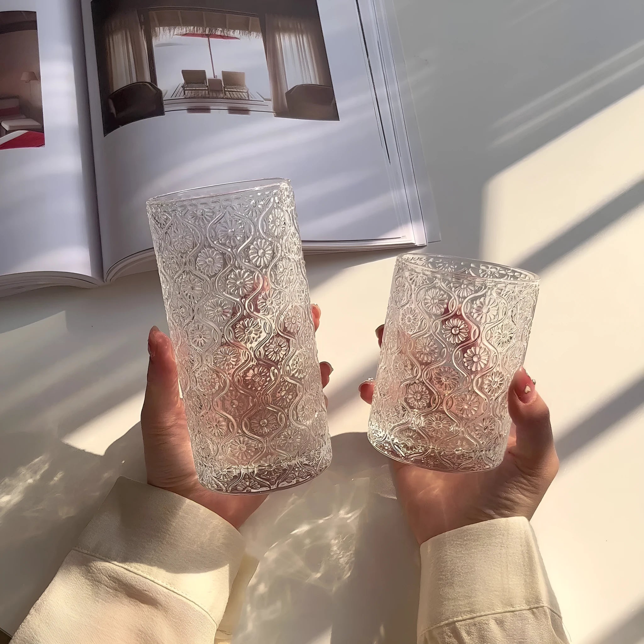 Begonia patterned glass drinking cup in short and tall sizes on a table.