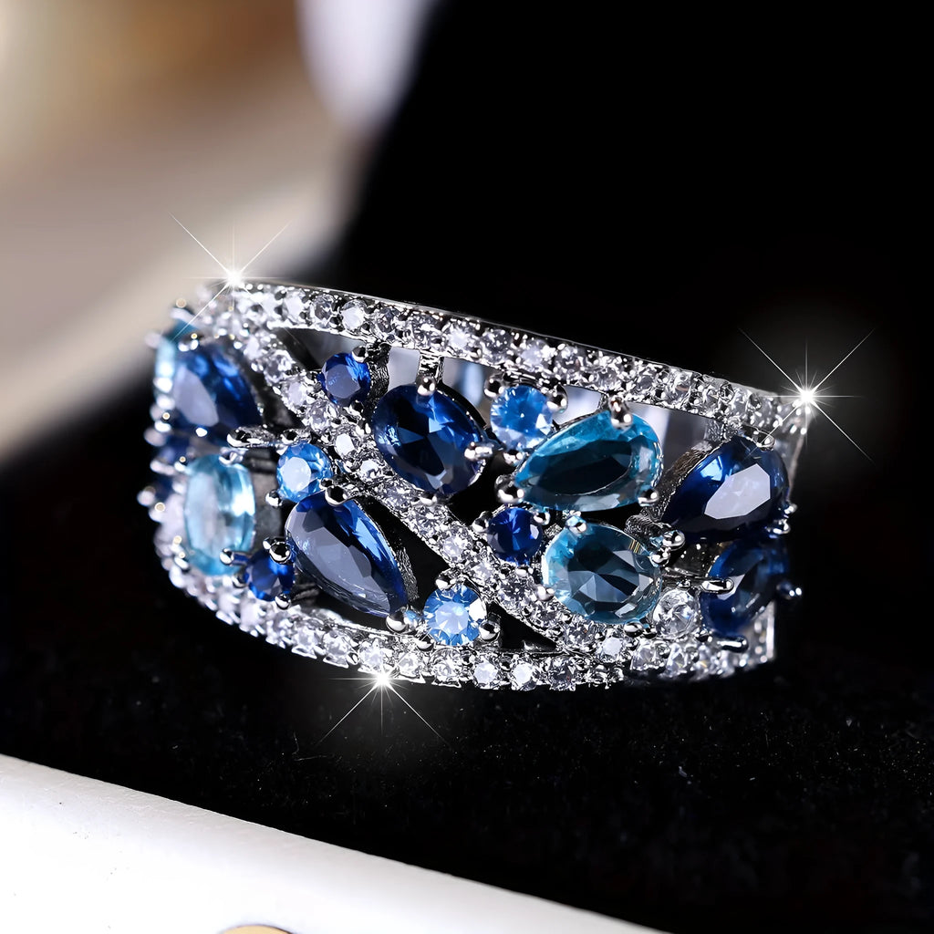 Women's round hollow copper fashion ring on a hand, showing gold and platinum finish options with blue and white accents.