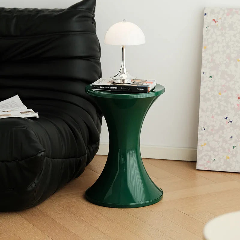 Green plastic hourglass-style shoe changing stool on a wooden floor.