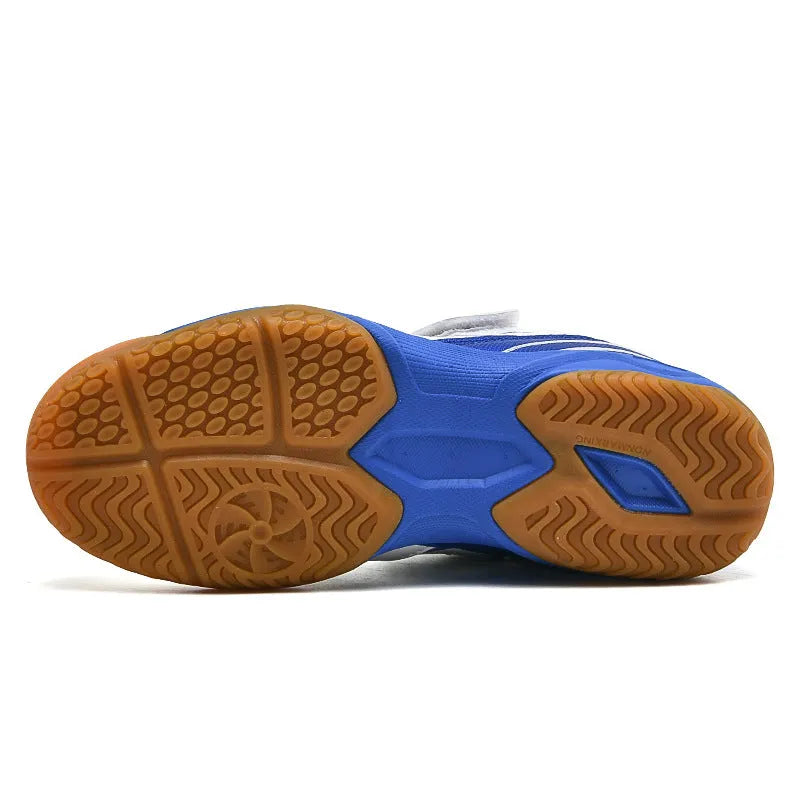 White and blue children's low-top badminton shoes with a ribbed sole on a court surface.