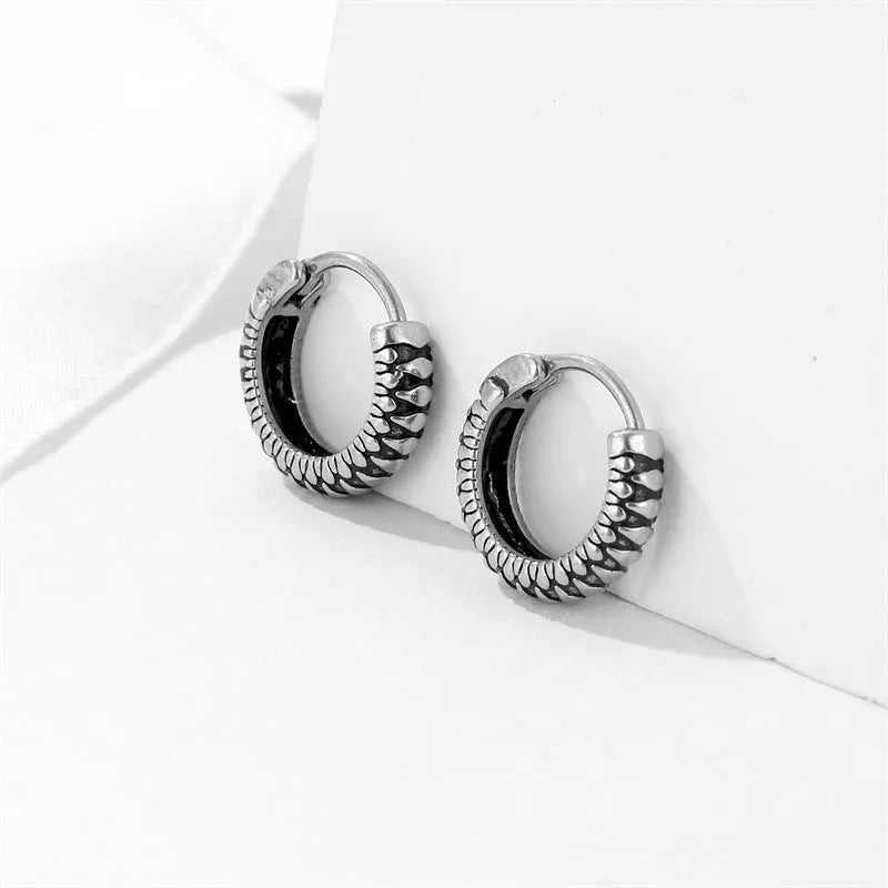 A pair of silver geometric twist earrings made from stainless steel alloy on a white background.