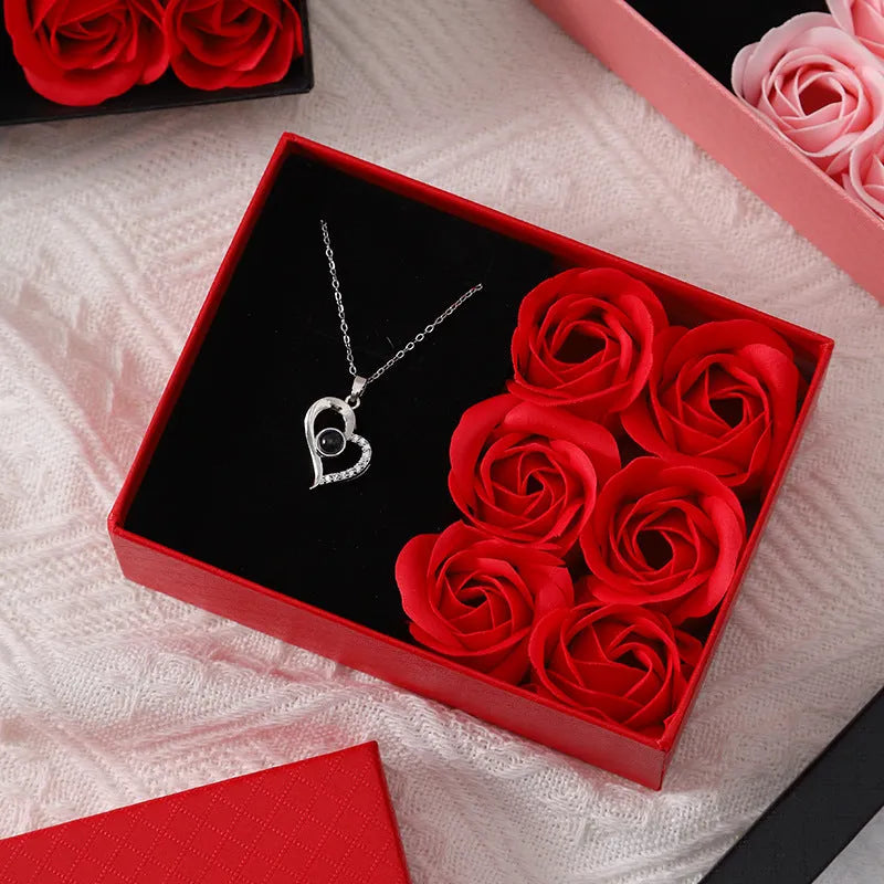 Red Valentine's gift box containing six pink soap flowers, with a matching red handbag alongside.