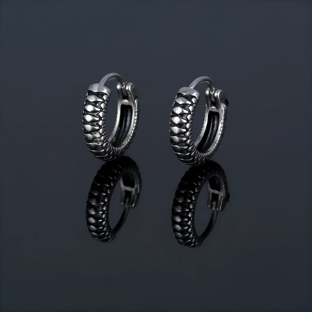 A pair of silver geometric twist earrings made from stainless steel alloy on a white background.