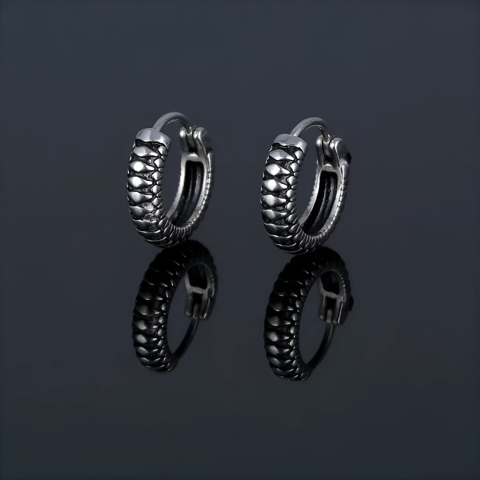 A pair of silver geometric twist earrings made from stainless steel alloy on a white background.