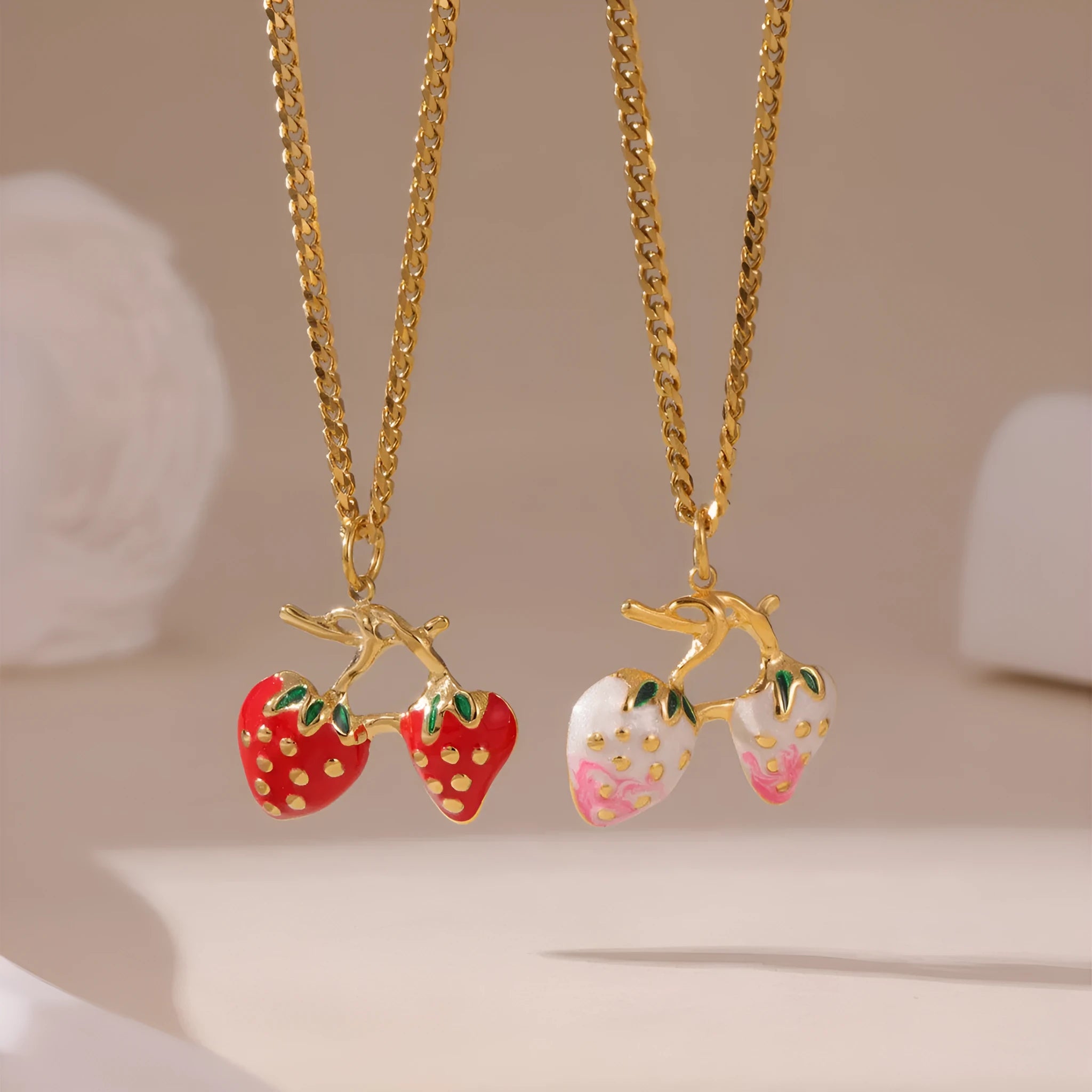 A women's necklace with a detailed strawberry-shaped alloy pendant on a stainless steel chain, shown in red and white gradient colour options.